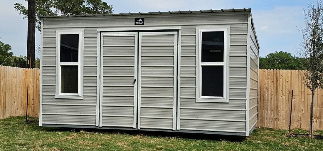 Custom metal storage shed with gable roof installed in a San Antonio backyard.