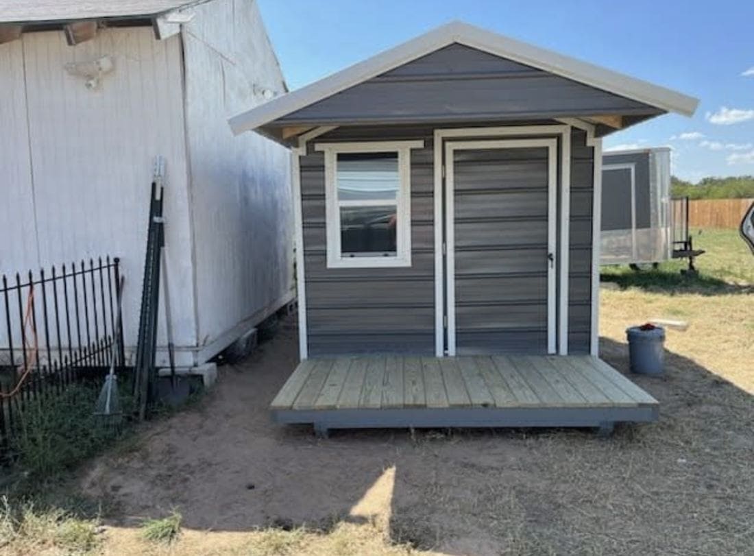 Large backyard utility shed with double doors and trim detailing in Bexar County.